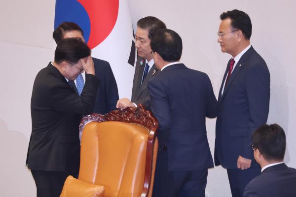 National Assembly Speaker Woo Won-shik (left) holds his forehead while speaking with floor leaders of the Democratic Party of Korea and the People Power Party during a plenary session at the Assembly in Seoul on Thursday, as tensions flared over the ruling party’s push for a government reorganization bill. The clash followed a disputed fast-track vote on the Democratic Meritorious Persons Act, where 257 ballots were counted despite only 256 lawmakers present. The main opposition party demanded a revote, but Woo rejected the request.  (Yonhap)