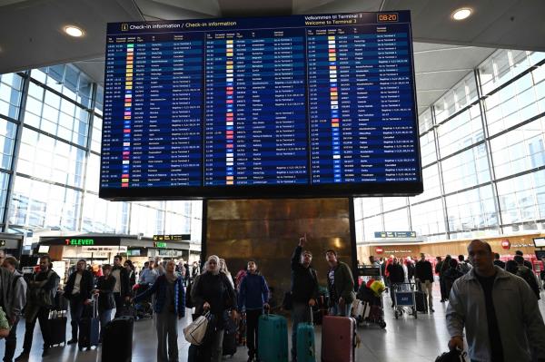 Passengers check a bord displaying flight informations at the Copenhagen Airport in Copenhagen, Denmark, Tuesday. (AFP-Yonhap)