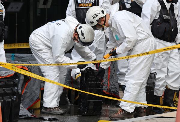 Police officials inspect the lithium-ion battery that caught on fire during Friday