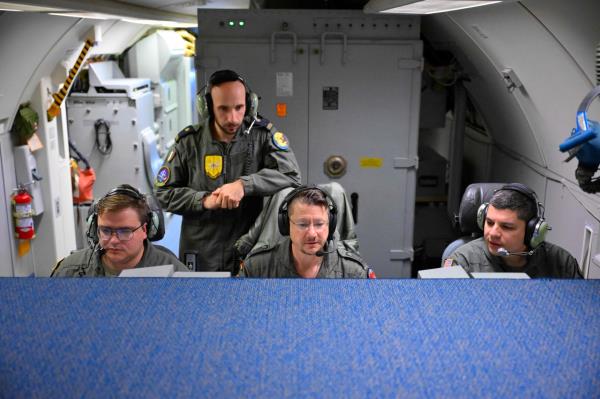 NATO surveillance operators work on computers aboard an aircraft during a flight over Polish airspace on Friday. (AFP-Yonhap)
