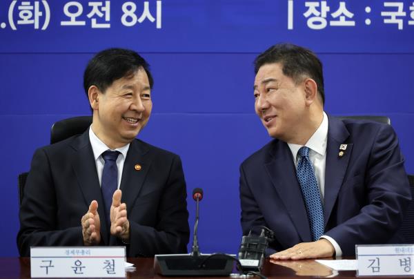 Kim Byung-ki (R), floor leader of the ruling Democratic Party, speaks with Finance Minister Koo Yun-cheol during a party-government consultation at the National Assembly in Seoul on Tuesday. (Yonhap)