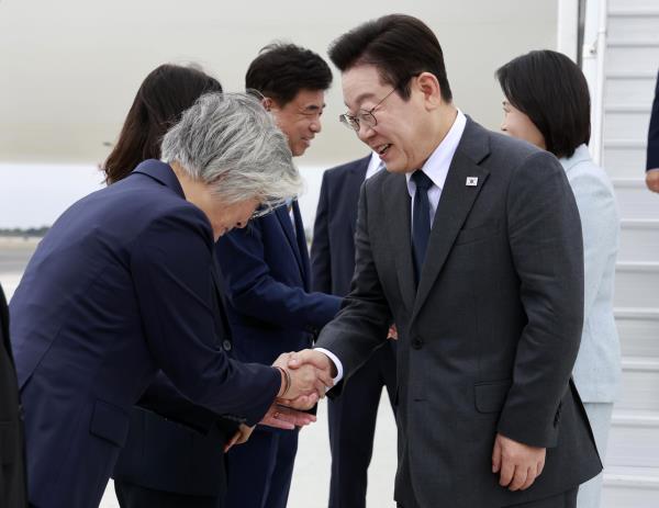 President Lee Jae Myung (right, front) shakes hands with Kang Kyung-wha (left, front), who is a nominee for the ambassador to the US, as Lee and his wife Kim Hea Kyung (right, back) disembark from Air Force One at the John F. Kennedy International Airport in New York Monday. (Yonhap)