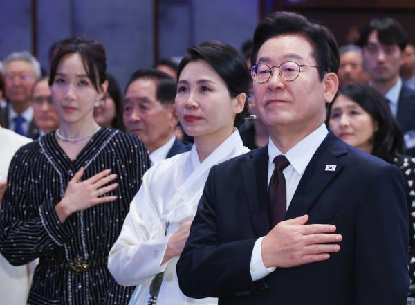 President Lee Jae Myung (right) and his wife Kim Hea Kyung (second from right), pay respects to the national flag during their meeting with overseas Koreans in New York Monday. (Yonhap)