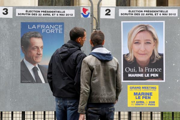 People stop to read the official campaign posters for French presidential candidates Nicolas Sarkozy (left) and Marine Le Pen (right) in Paris in 2012. (Reuters-Yonhap)